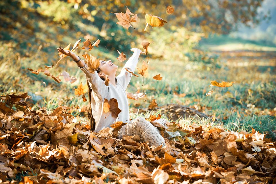 Glückspilze: Lachendes Mädchen wirft Blätter in die Luft