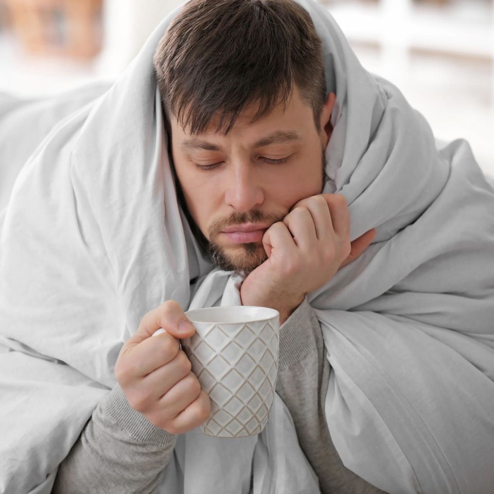 Männergrippe: Mann mit Decke und Tee