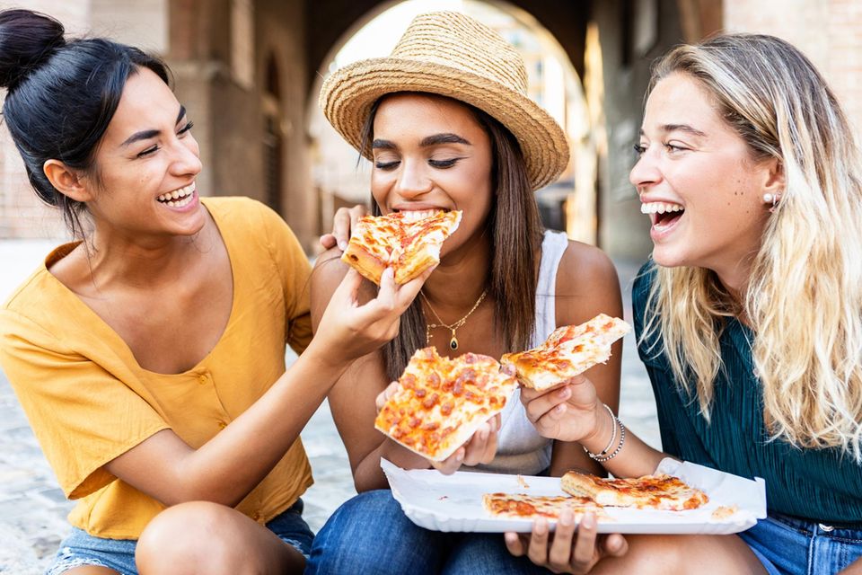 7 Angewohnheiten, die deiner Darmflora schaden: Drei Frauen essen Pizza.