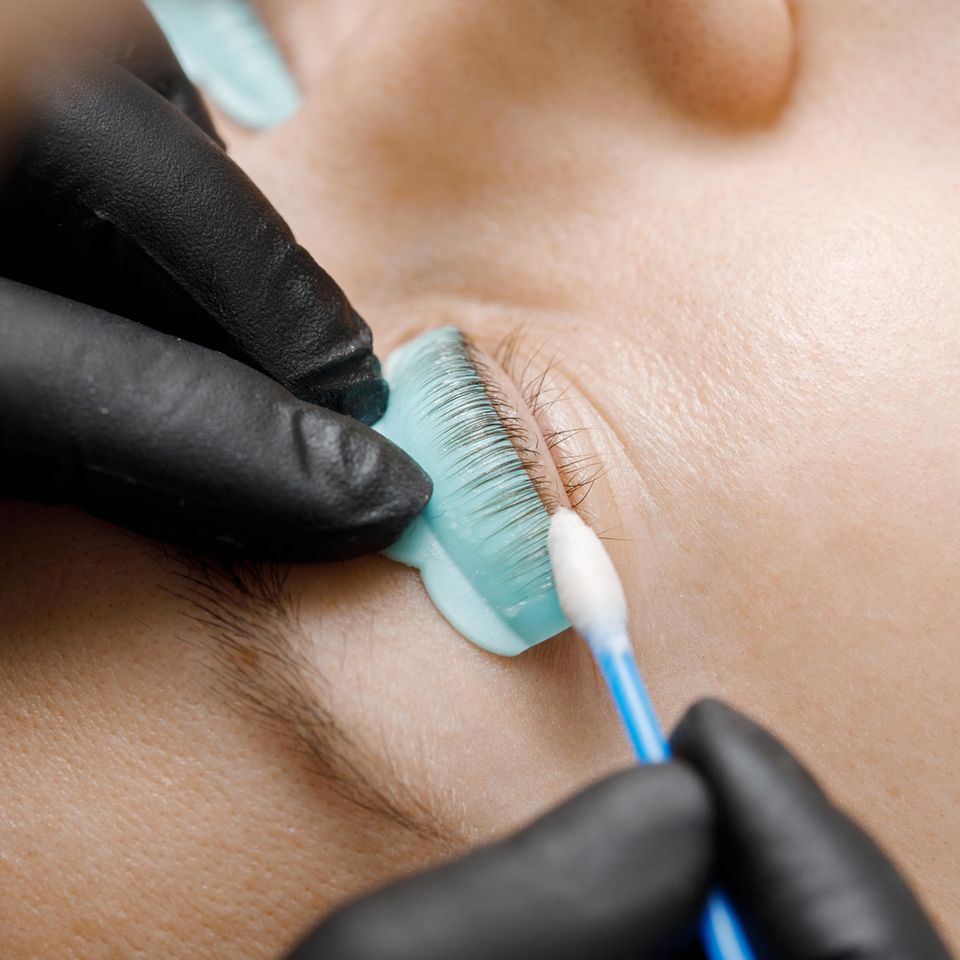 Wimpernlifting Set: Auge mit Silikonkissen, zwei Hände, die Wimpernlifting machen