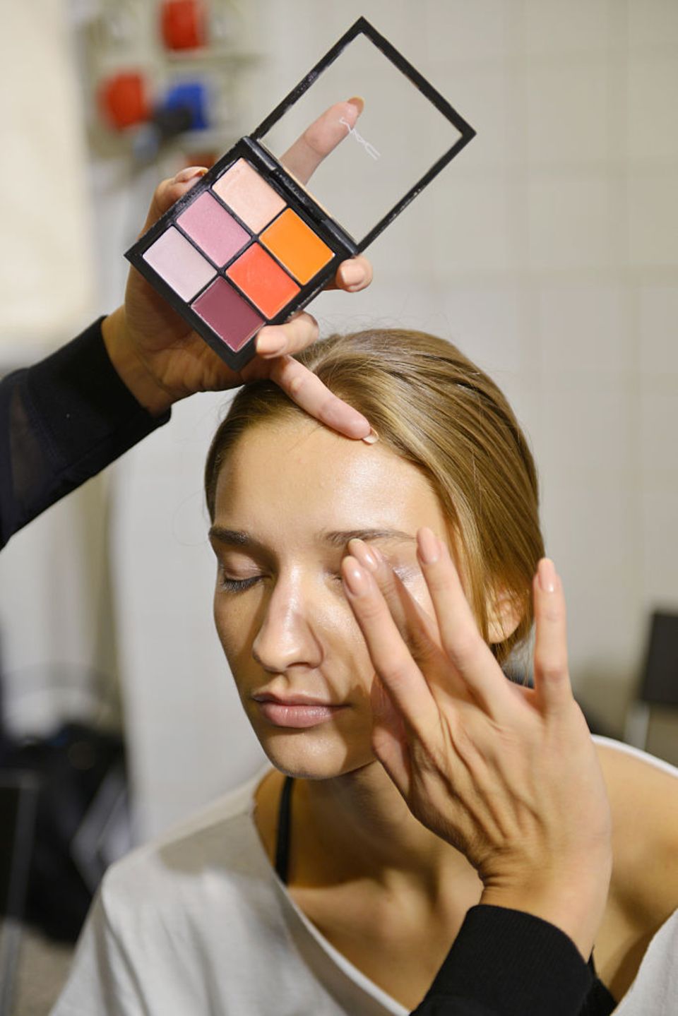 Make-up Artist trägt Lidschatten von MAC mit dem Finger auf