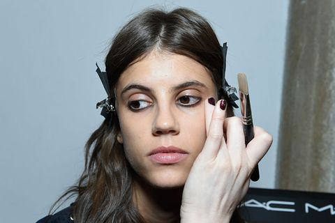 Make-up Artist trägt Foundation von MAC mit dem Finger auf