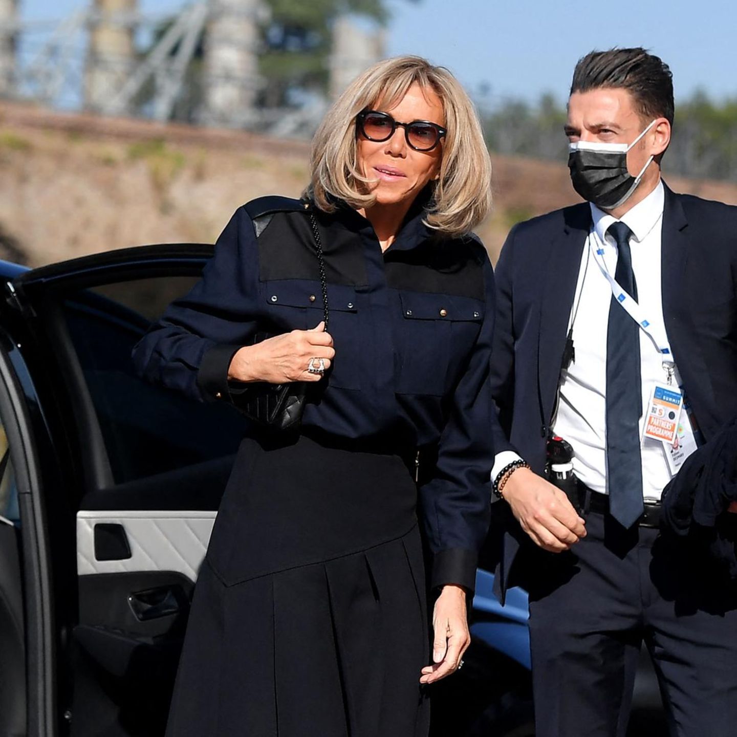 Am Rande des G20-Gipfels 2021 stattet Brigitte Macron dem Kolosseum in Rom einen privaten Besuch ab. Die Frau des französischen Präsidenten trägt eine dunkelblaue Oversized-Bluse. Macron kombiniert das moderne Piece mit einem hochgeschnittenen Faltenrock in Schwarz und einer gleichfarbigen kleinen Handtasche. Den sportlich schicken Auftritt rundet die Französin mit einer schwarzen Sonnenbrille und silbernem Schmuck ab. 