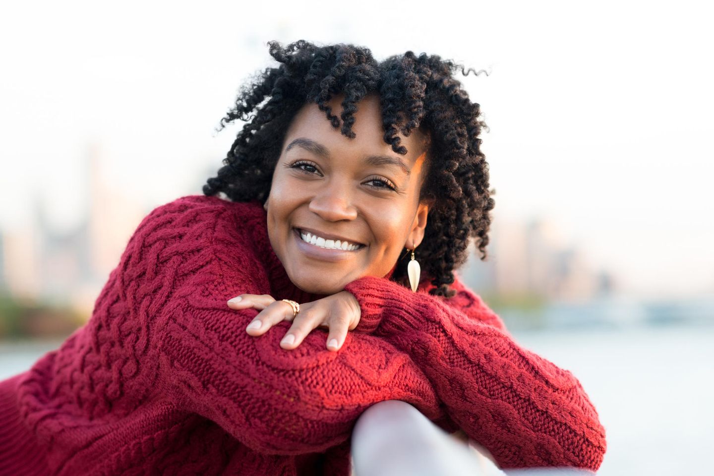 Persönlichkeit: Lachende Frau trägt roten Wollpullover