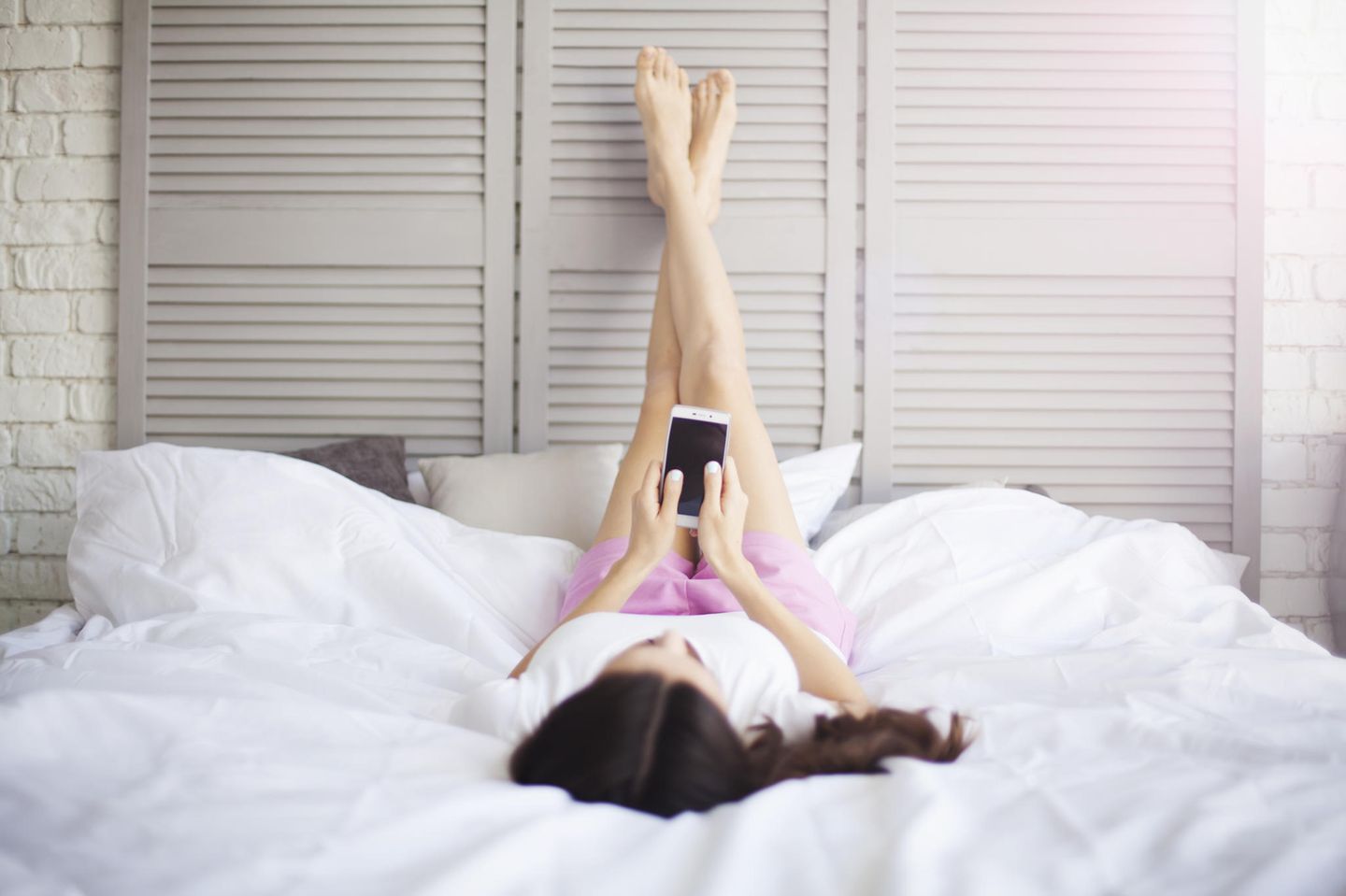 Wadenkrampf-Ursachen: Frau liegt auf dem Bett