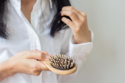 Haarausfall im Alter: Frau untersucht Haare in einer Bürste
