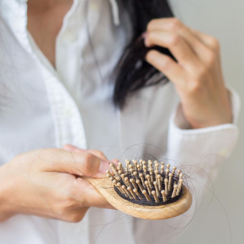 Haarausfall im Alter: Frau untersucht Haare in einer Bürste
