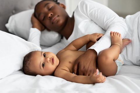 Mutter zeigt anhand von Daten, wie anstrengend ihre Elternzeit ist: Mutter liegt mit ihrem Baby auf dem Bett