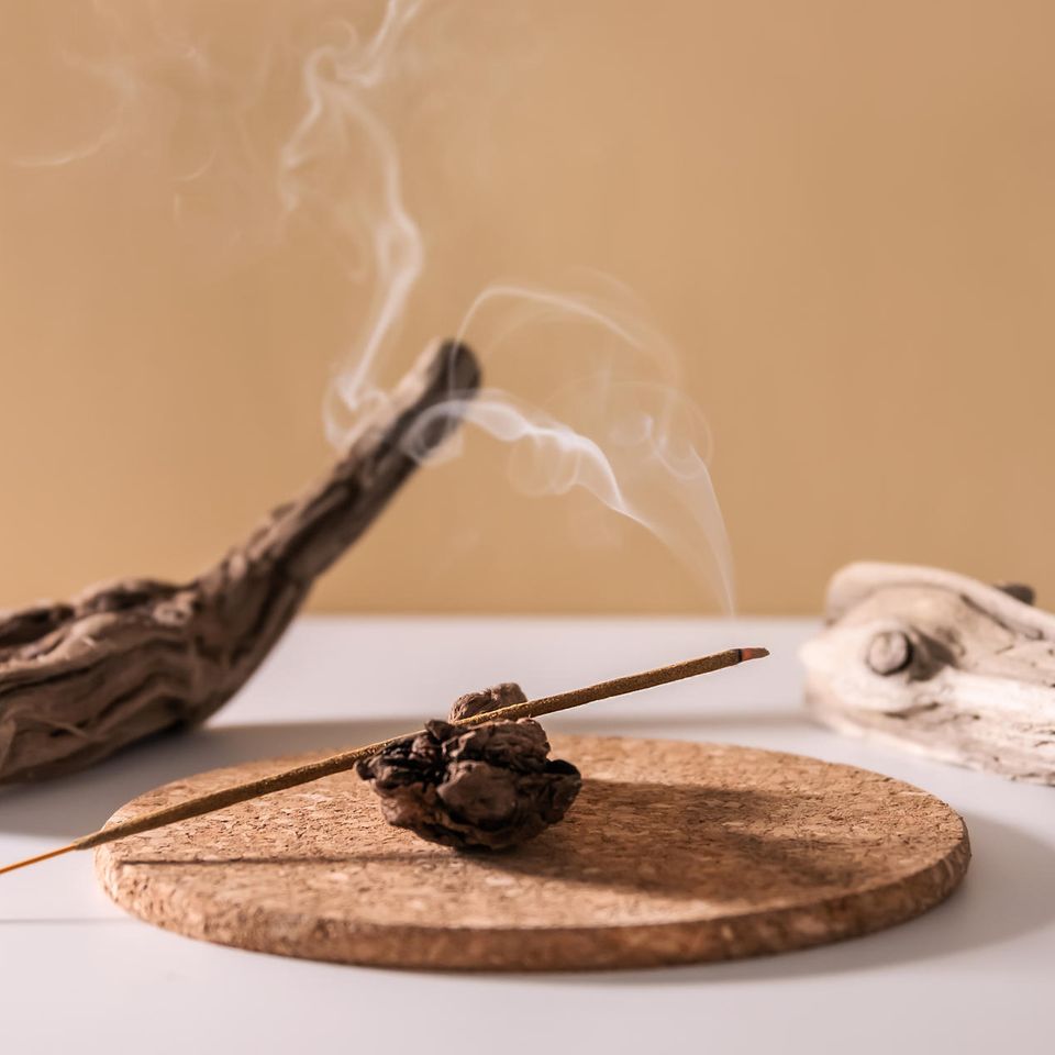 Brennende aromatische Räucherstäbchen auf minimalistischem Holzhintergrund