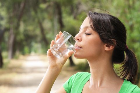 Dinge, die wir nie tun würden: Frau trinkt ein Glas voller Wasser draußen