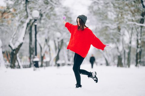 Horoskop ab Dezember 2021: Frau in roter Jacke läuft durch den Schnee