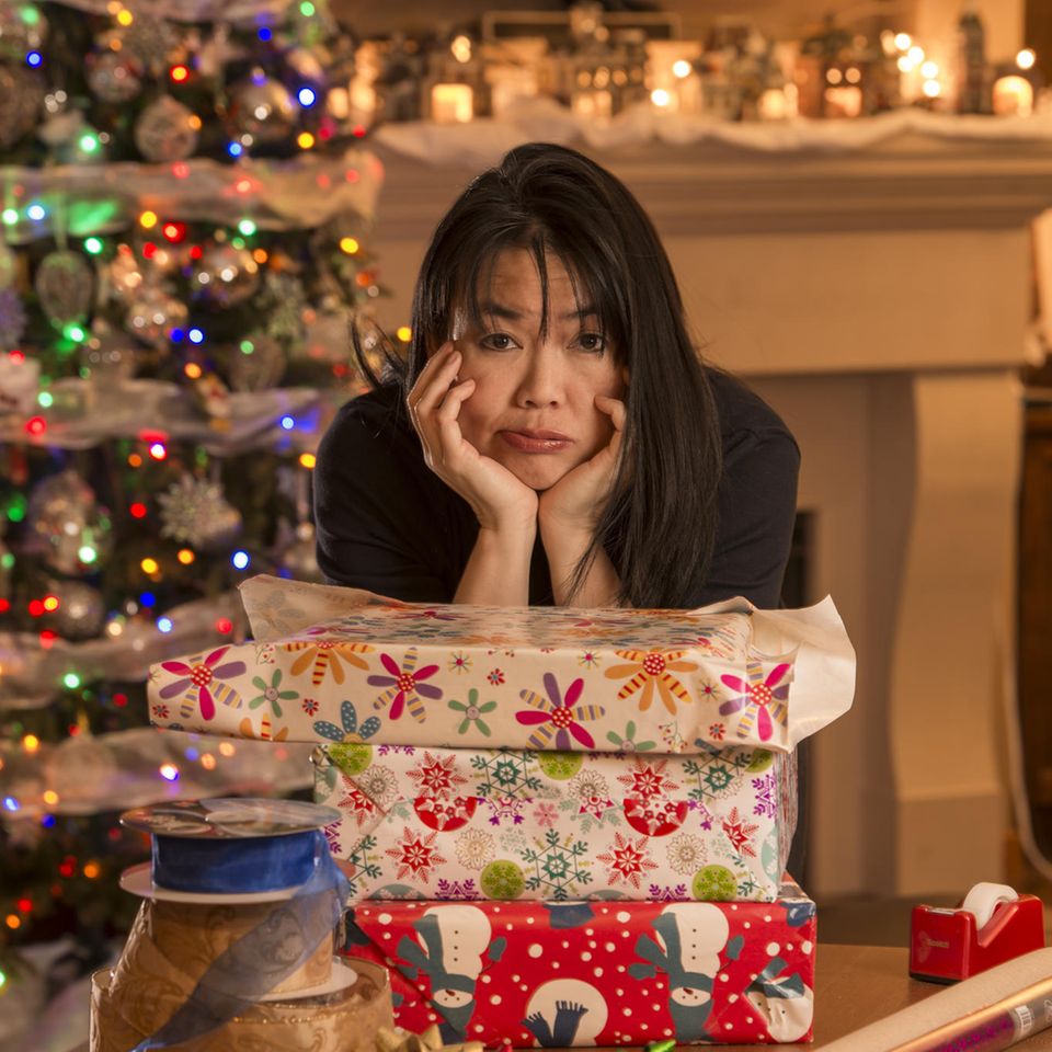 Eine Frau stütz sich verzweifelt auf Weihnachtsgeschenke.