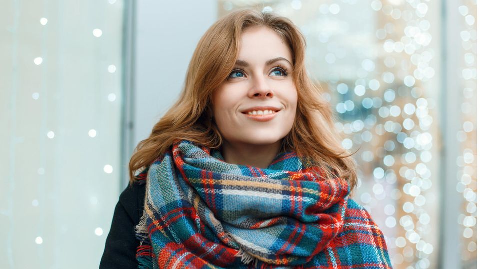 Horoskop: Lächelnde rothaarige Frau mit kariertem Schal