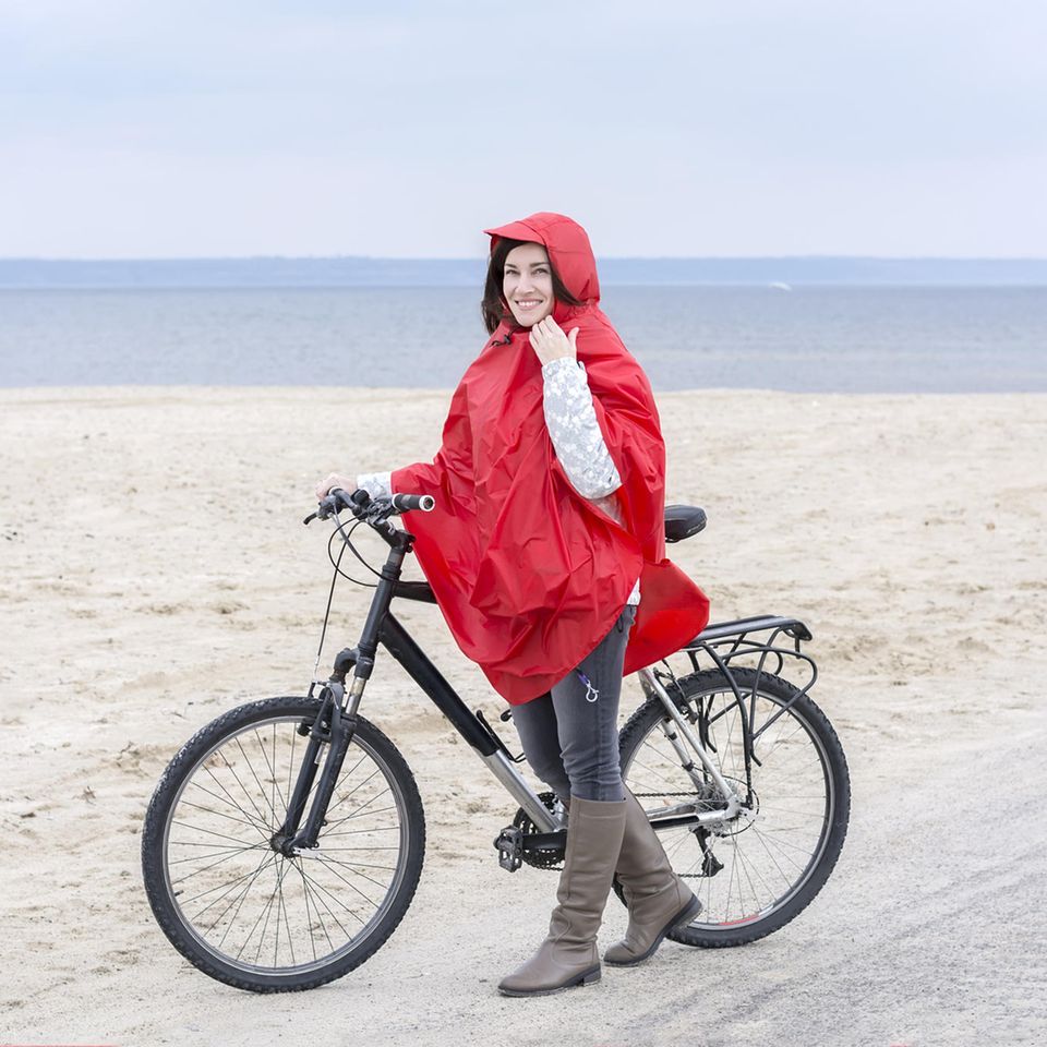 Regenponcho fürs Fahrrad: Diese 6 Modelle halten dich sicher trocken, Frau, Fahrrad, roter Regenponcho, Strand