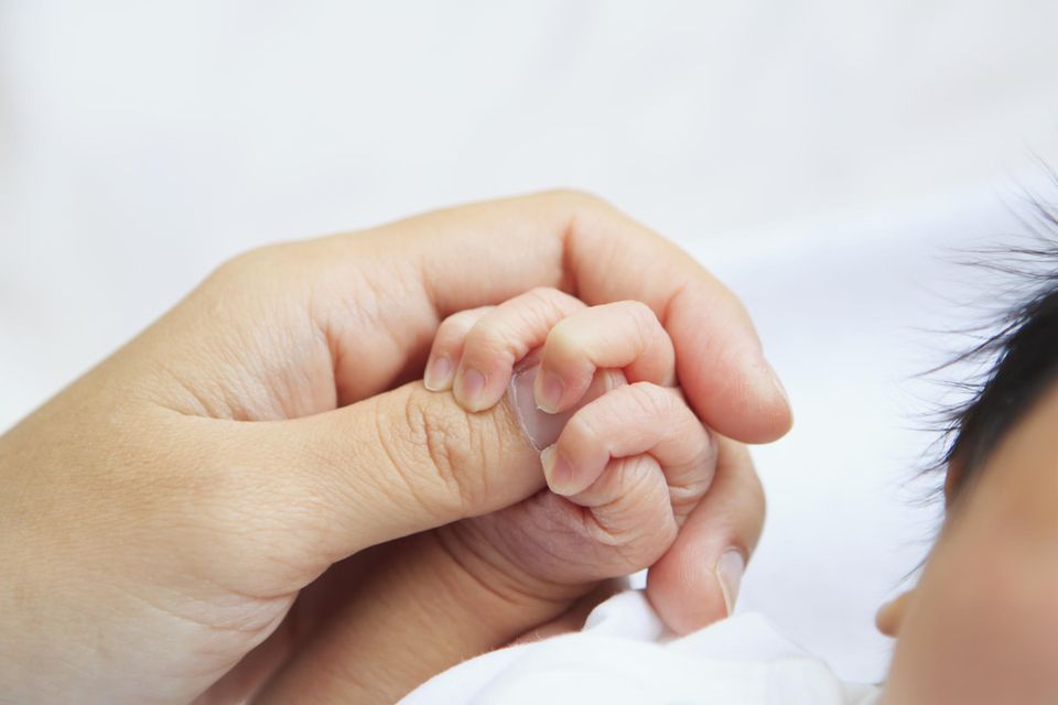 Frau wird mit 50 erstmals Mutter: Hand der Mutter hält Hand vom Baby