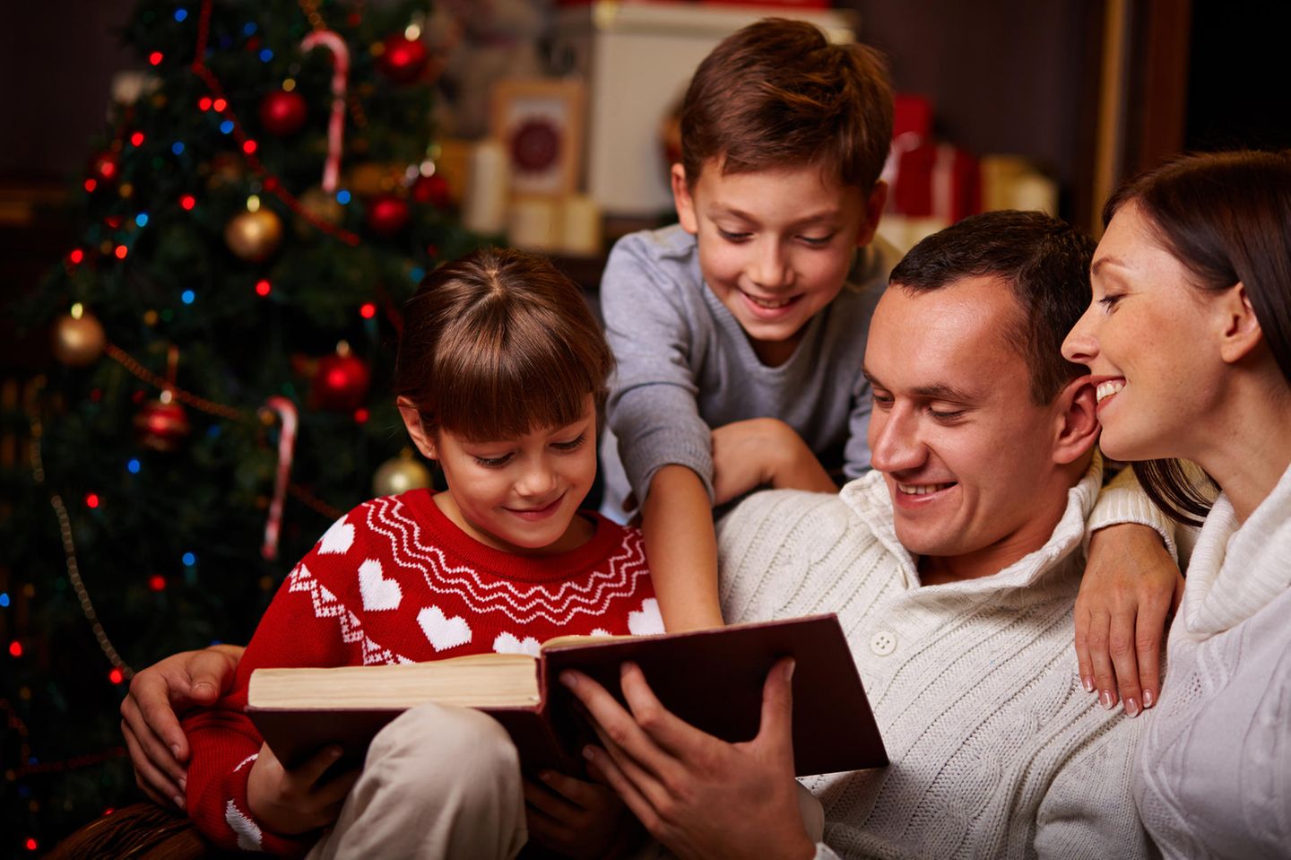 Vierköpfige Familie liest Weihnachtsbuch