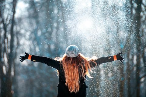 Horoskop: Frau im Schnee streckt Arme zu den Seiten