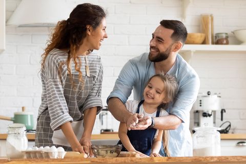 Aufgabenverteilung: Ein Paar- eine Frau und ein Mann stehen mit ihrer kleinen Tochter in der Küche und Backen.