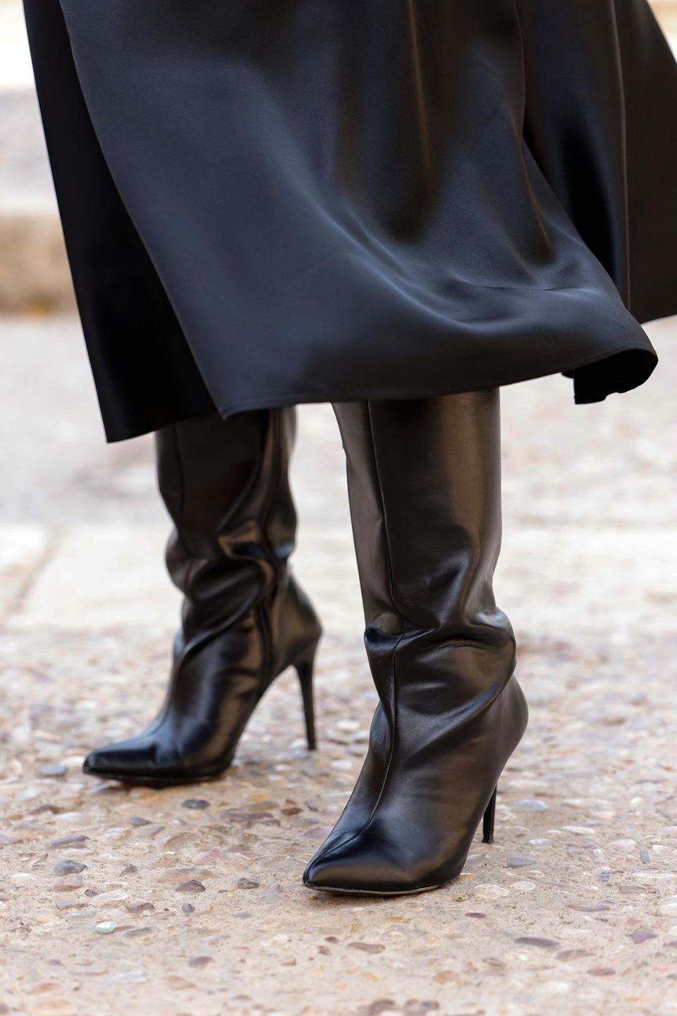 Eine Frau trägt schwarze Overknee-Stiefel und einen schwarzen Rock