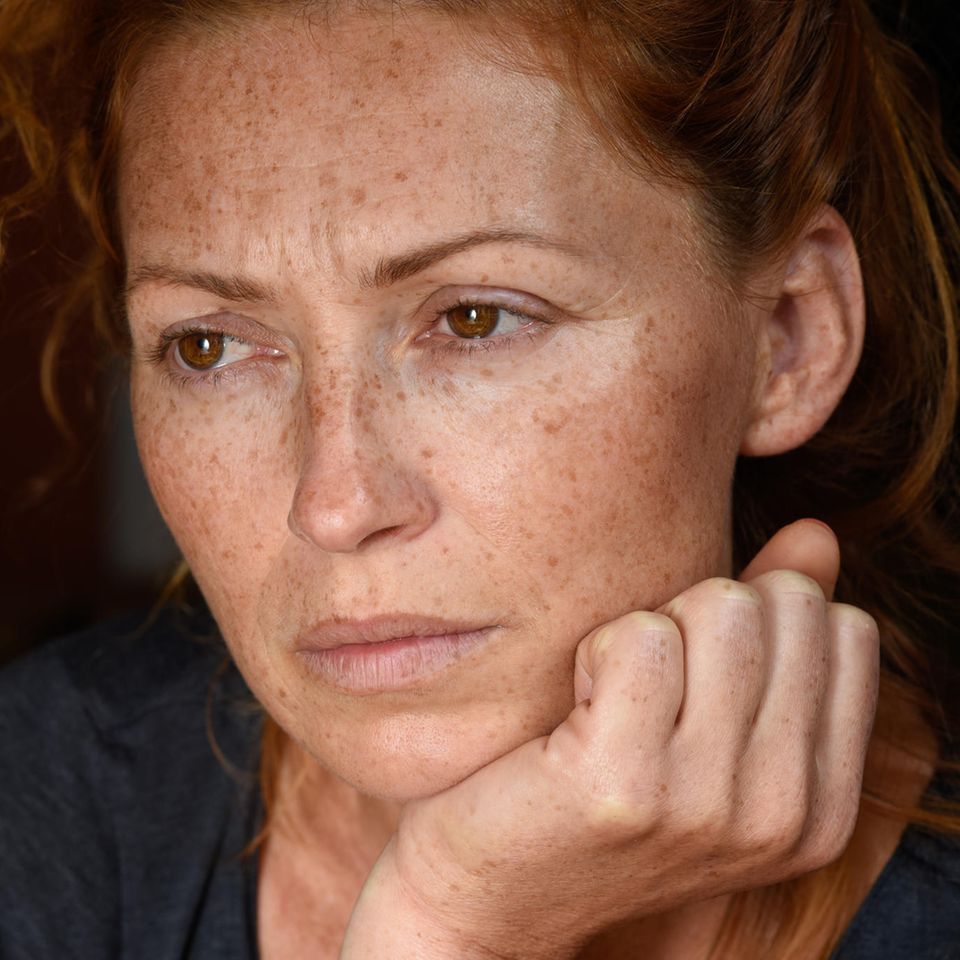 Psychologie: Nachdenkliche rothaarige Frau schaut aus dem Fenster