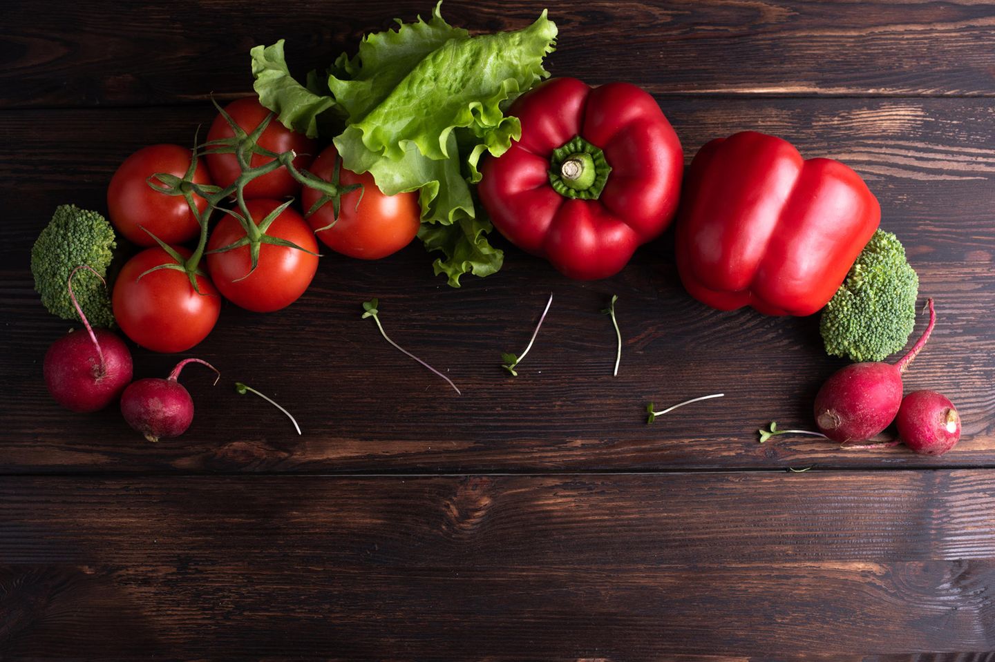 Epi-Food: Gemüse, das in einem Halbkreis auf einer dunklen Holzplatte liegt