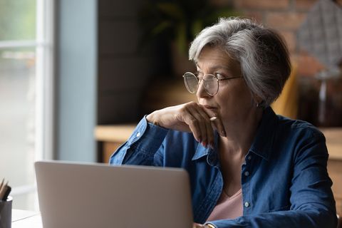 Verschwörungstheoretiker in der Familie: Eine ältere Dame sitzt vor einem Laptop und guckt nachdenklich