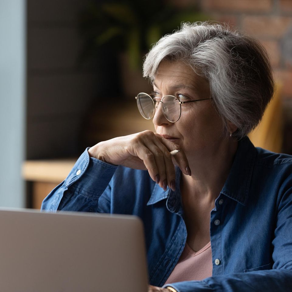 Verschwörungstheoretiker in der Familie: Eine ältere Dame sitzt vor einem Laptop und guckt nachdenklich