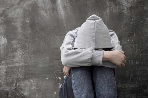 Suizidversuche bei Kindern: Teenager kauert an Wand