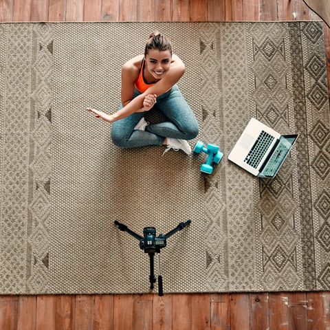 Fitnesstrends: Frau trainiert vor dem Laptop