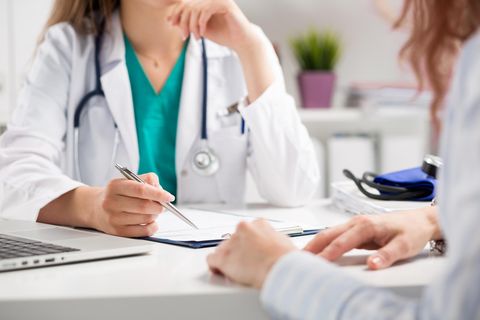 Björn Krause: eine Ärztin sitzt mit einer Patientin an einem Tisch mit einem Stift in der Hand und einem Formular