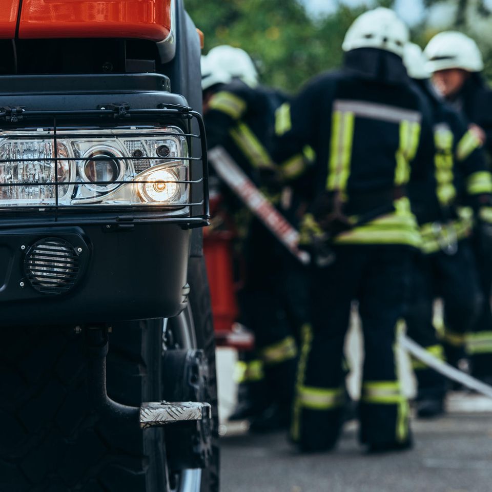 Thomas Hoppe: unscharfes Foto von Feuerwehrmännern, die neben einem Feuerwehrauto stehen