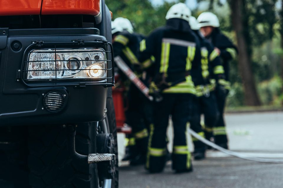 Thomas Hoppe: unscharfes Foto von Feuerwehrmännern, die neben einem Feuerwehrauto stehen