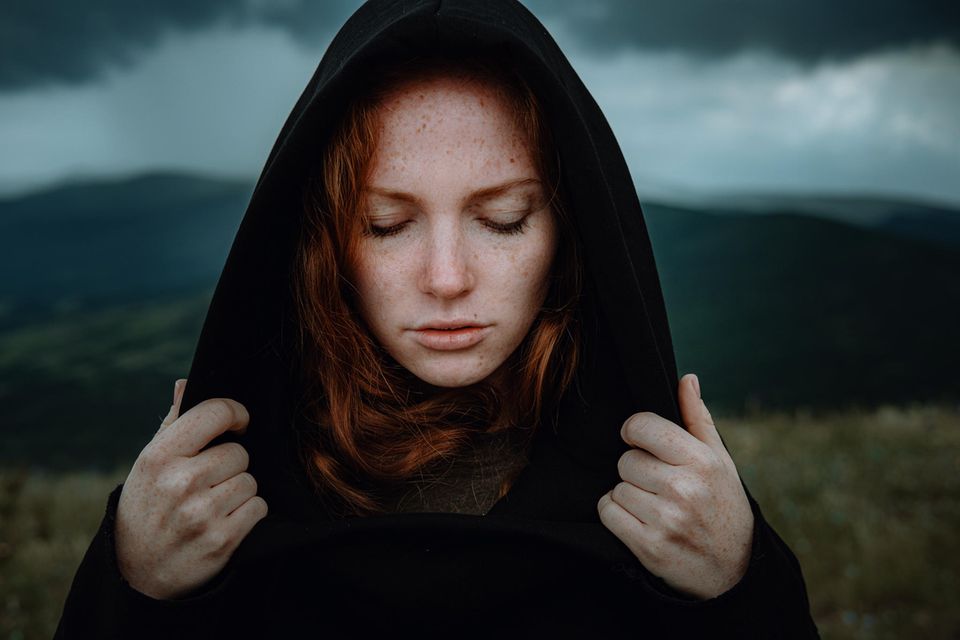 Eine Frau ist draußen und schaut traurig zu Boden.