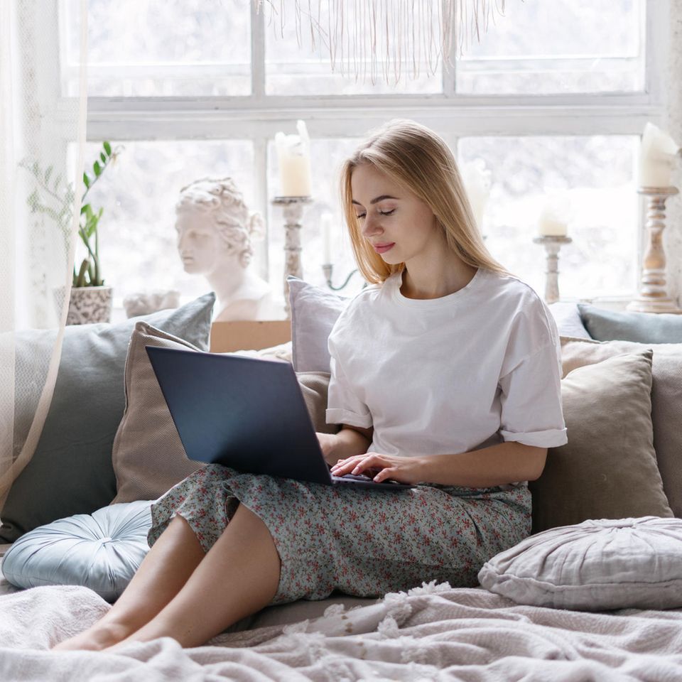 Arbeit aus dem Bett: Eine junge blonde Frau sitzt mit einem Laptop im Bett
