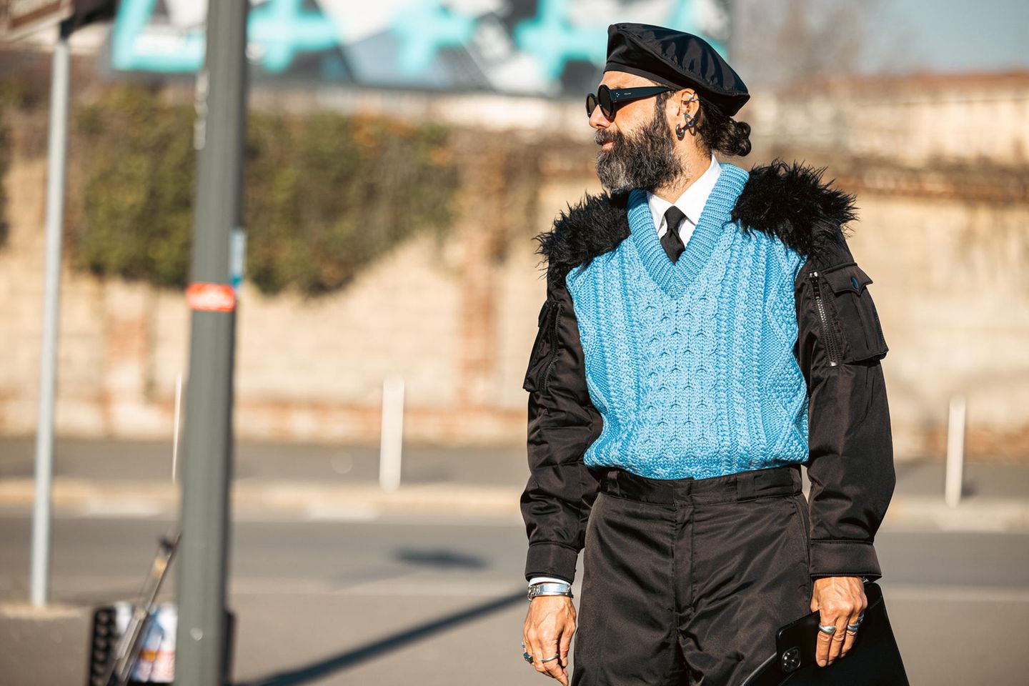 Streetstyles sollen und dürfen außergewöhnlich sein - vor allem auf der Fashion Week in Mailand. Der Look von Graziano di Cintio für die Frühjahr-/Sommerkollektion 2022 von Prada Menswear sticht dort ganz besonders ins Auge. Er trägt einen farbenfrohen Pullunder, bei dem die Schultern mit Fell besetzt sind. Ein besonderes Outfit, das zu ihm passt, aber sicherlich als skurril betrachtet werden darf. Auch die Bomberjacke, die er drunter trägt, macht es zu einem merkwürdigen Look.