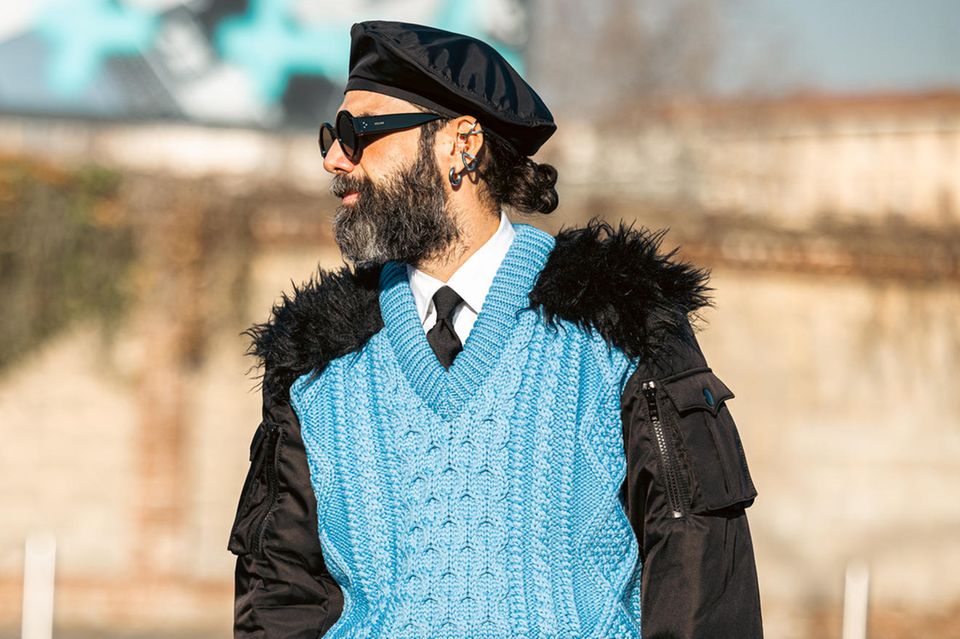 Streetstyles sollen und dürfen außergewöhnlich sein - vor allem auf der Fashion Week in Mailand. Der Look von Graziano di Cintio für die Frühjahr-/Sommerkollektion 2022 von Prada Menswear sticht dort ganz besonders ins Auge. Er trägt einen farbenfrohen Pullunder, bei dem die Schultern mit Fell besetzt sind. Ein besonderes Outfit, das zu ihm passt, aber sicherlich als skurril betrachtet werden darf. Auch die Bomberjacke, die er drunter trägt, macht es zu einem merkwürdigen Look.