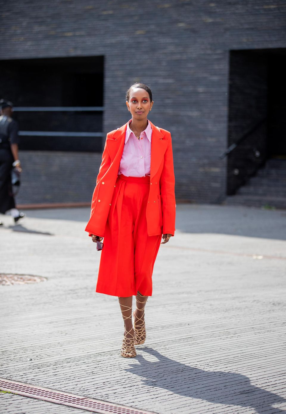 Eine Frau in rotem Zweiteiler und rosa Bluse auf der Copenhagen Fashion Week 2021