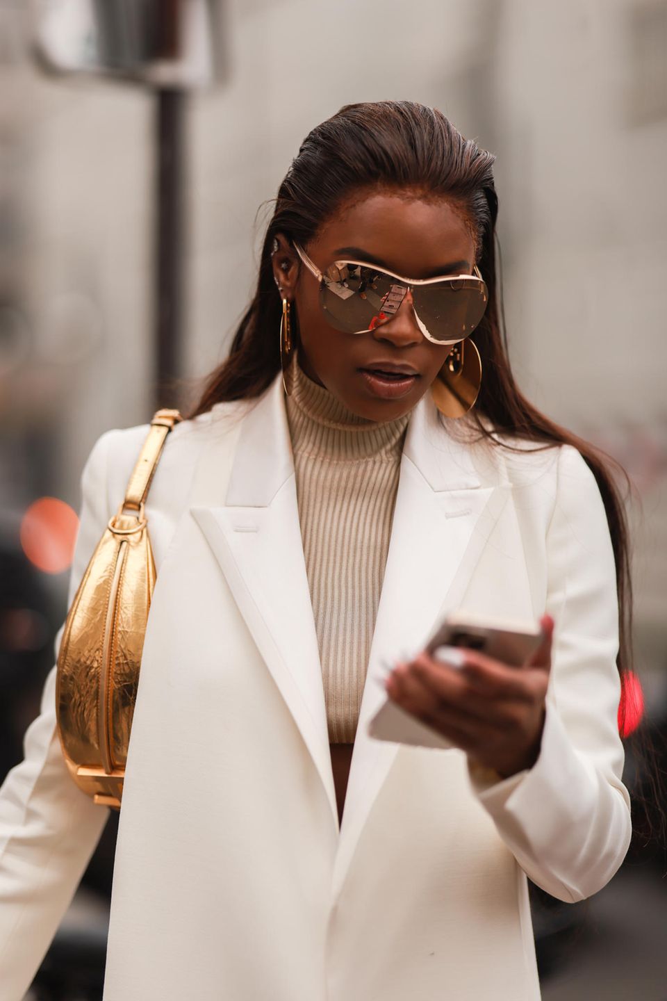 Streetstyle: Frau mit cremefarbenem Blazer und goldener Handtasche