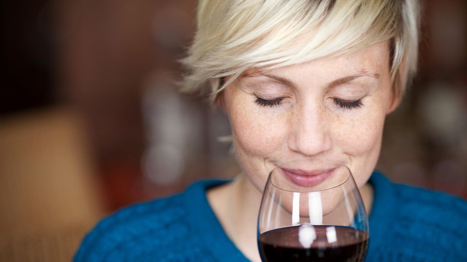 Eine Frau riecht genüßlich an einem Glas Rotwein.