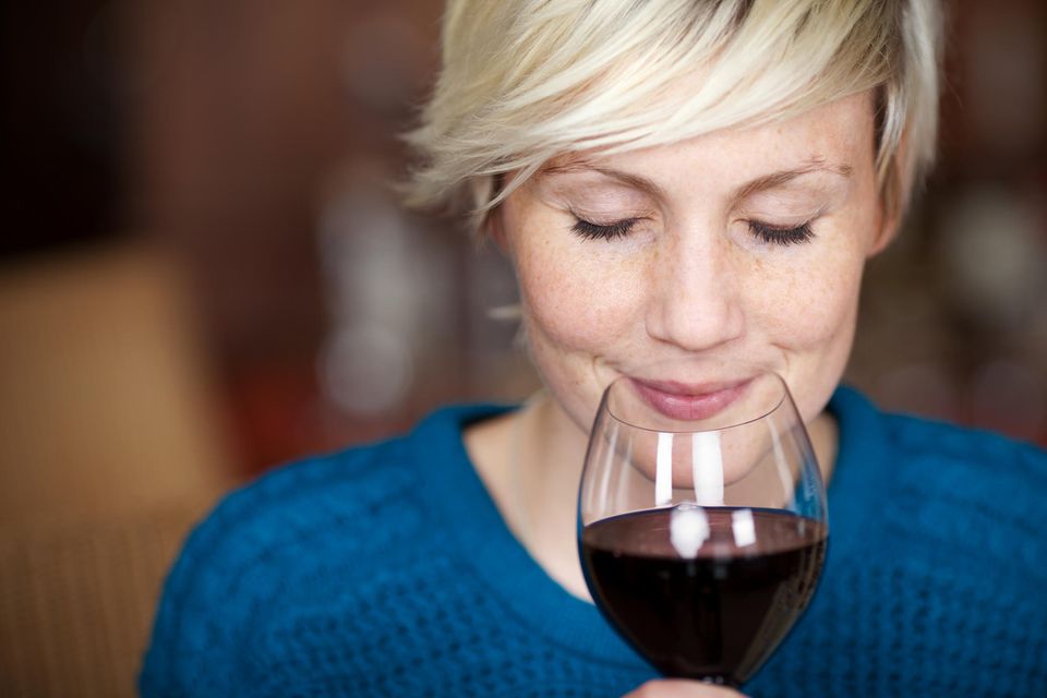 Eine Frau riecht genüßlich an einem Glas Rotwein.