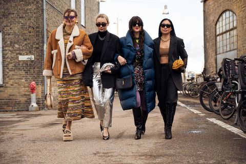 Vier Frauen laufen auf der Copenhagen Fashion Week durch eine Straße