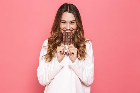 Glückliche Frau isst eine Tafel Schokolade