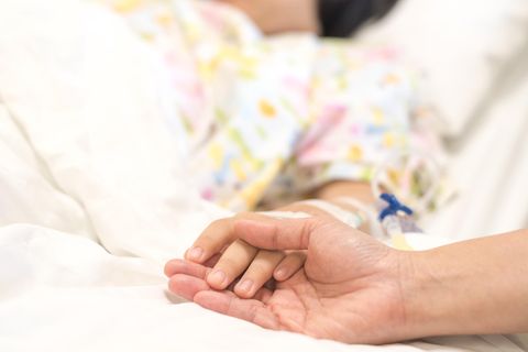 Eine ältere Hand hält die eines kranken Kindes