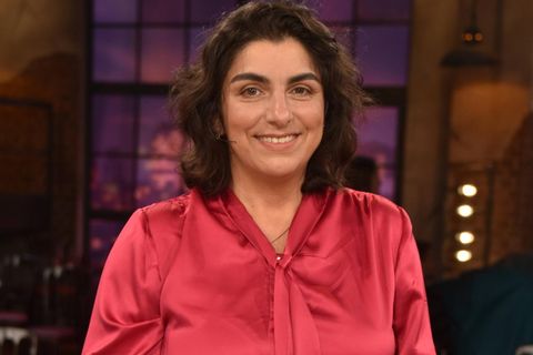 Dilek Gürsoy: Eine Frau mit pinker Seidenbluse und schulterlangen dunklen Haaren hält ein künstliches Herz
