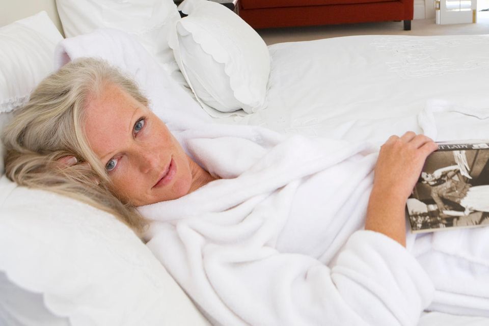 Easy: Frau mit Bademantel liegt auf dem Bett