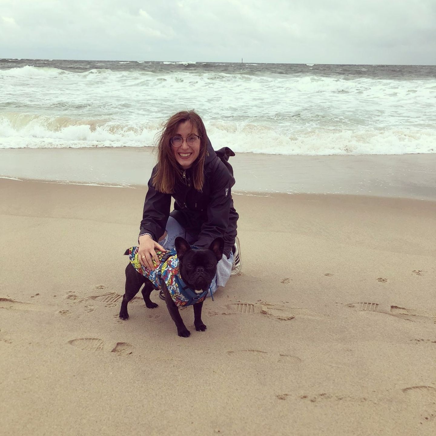 Liebe-dein-Haustier-Tag: Frau mit kleinem schwarzem Hund am Strand