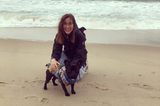 Liebe-dein-Haustier-Tag: Frau mit kleinem schwarzem Hund am Strand