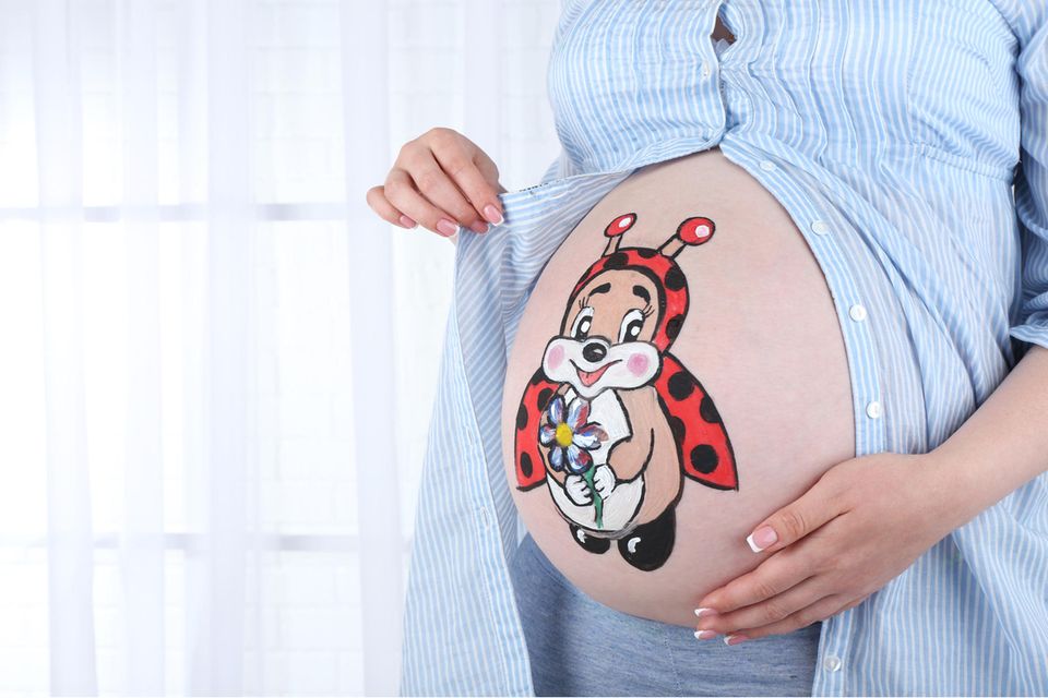 Babybauch bemalen: aufgemalter Marienkäfer auf Babybauch