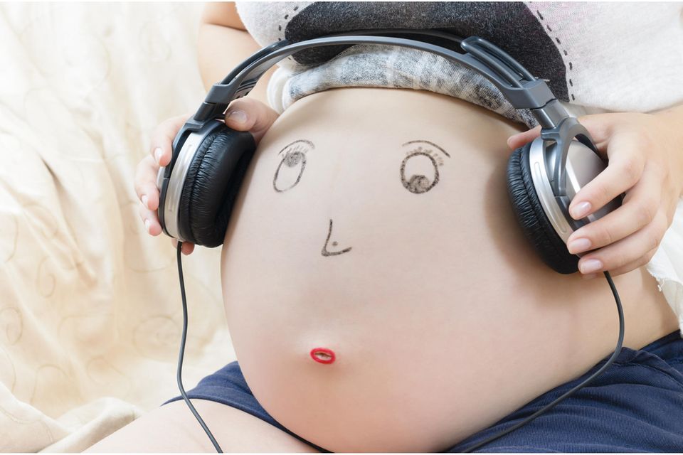 Babybauch bemalen: Aufgemaltes Gesicht mit Kopfhörern