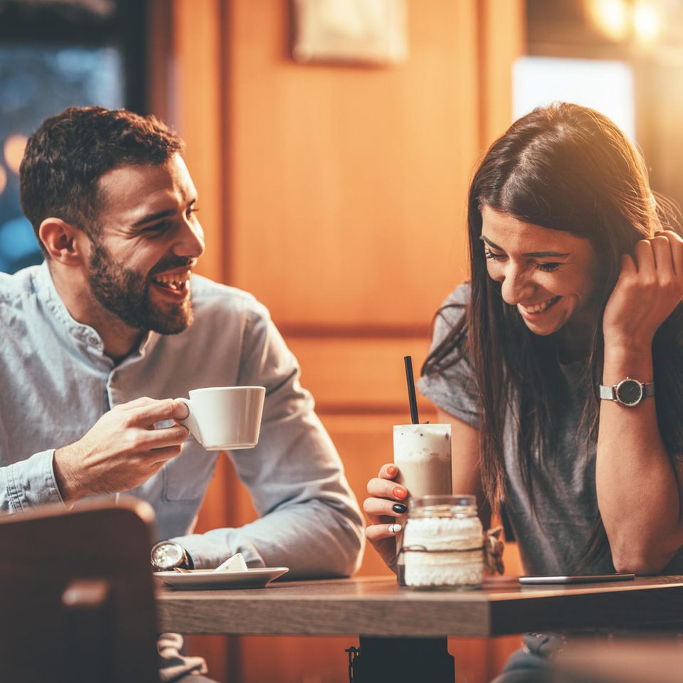 Der Funke: ein junges Paar setzt lachend an einem Tisch in einem Café
